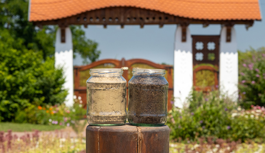 Two glass jars filled with soil are pictured in front of Eminence Organics' Farm